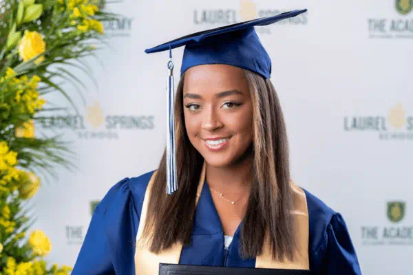 female graduate smiling at the camera in her gown and cap
